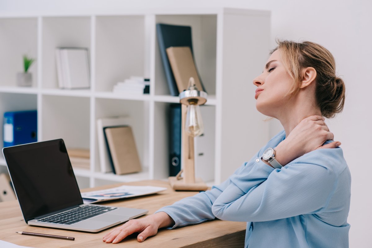 woman at desk rubbing her neck to ease neck pain